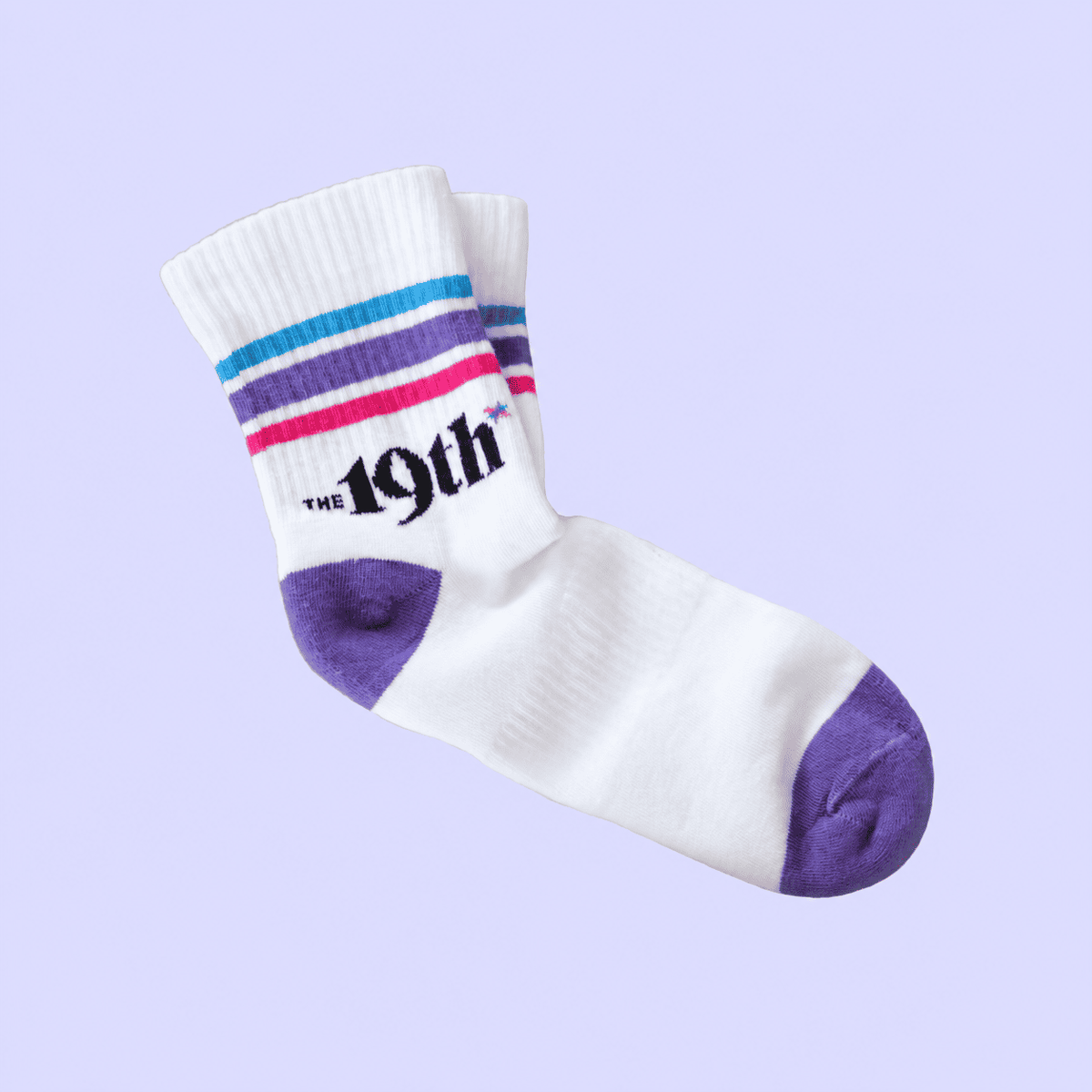 A pair of white crew socks with purple, blue, and pink stripes near the cuff, featuring the text 'THE 19th' in black. The toes and heels are solid purple.