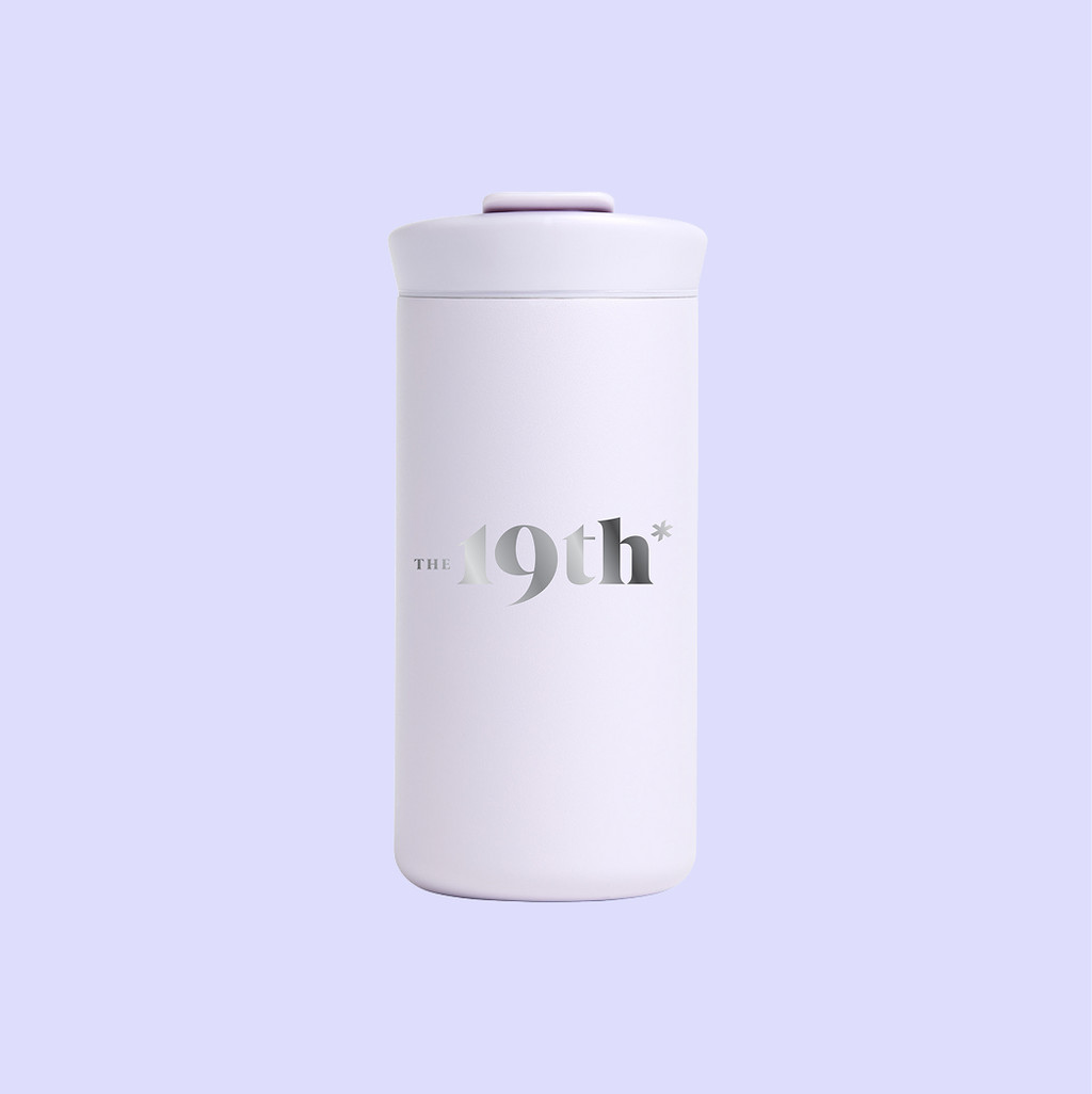 A lilac drinkware tumbler featuring The 19th's logo engraved on the front.